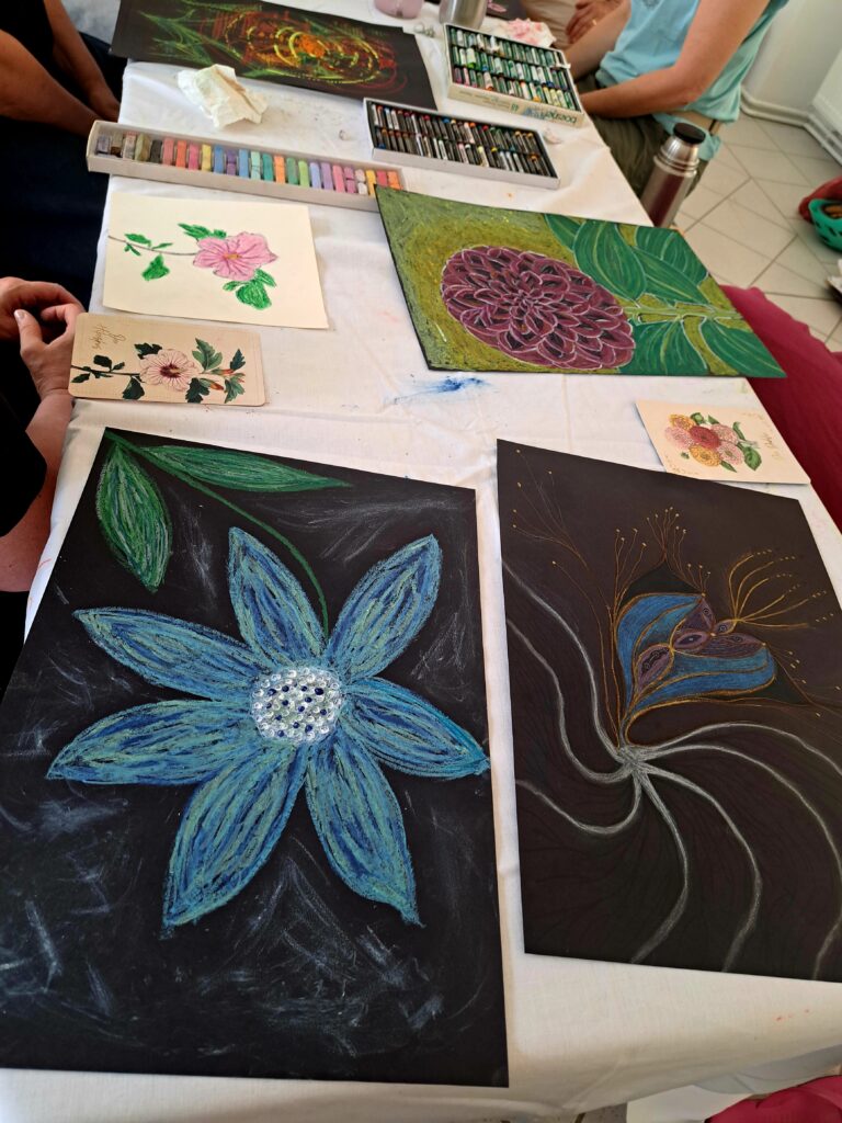 Teilnehmende des Kunsttreffs präsentieren ihre individuellen Blumenbilder und tauschen sich über ihre Bedeutungen und den kreativen Prozess aus.